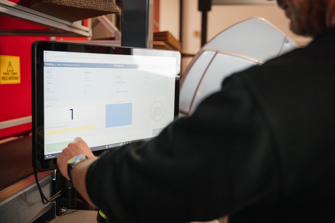 Un employé utilise un écran tactile pour préparer des commandes avec le système AutoStore