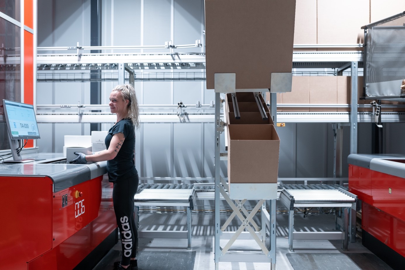 Une employée d’entrepôt emballe une commande depuis un port AutoStore.