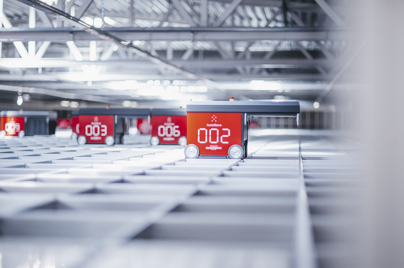 Une grille, parcourue par plusieurs robots AutoStore rouges qui participent à la préparation des commandes.